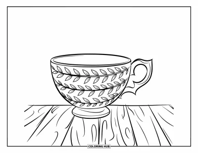 Coloriage de tasse à thé pour enfants : Tasse gravée de motifs de feuilles posée sur une surface en bois
